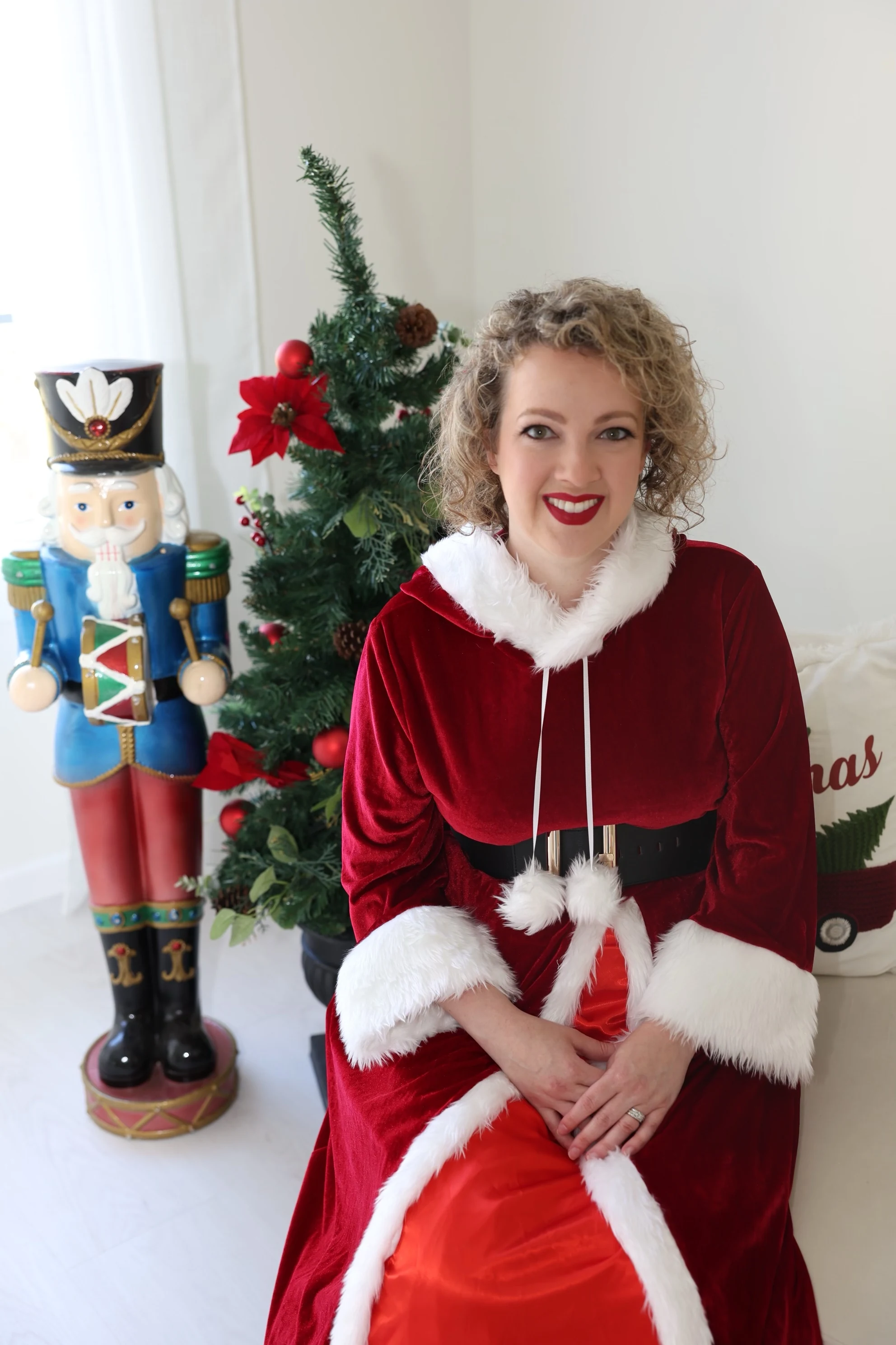 Mrs. Claus in her burgundy velvet dress beside a Christmas tree
